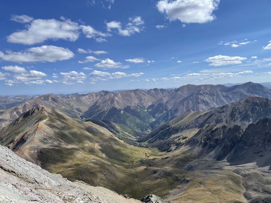 Folded ridges and a deep valley under scattered white clouds