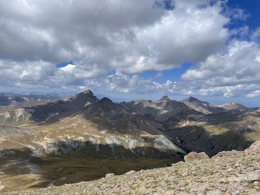 Jagged dark peaks beyond a high basin, heavy white clouds overhead