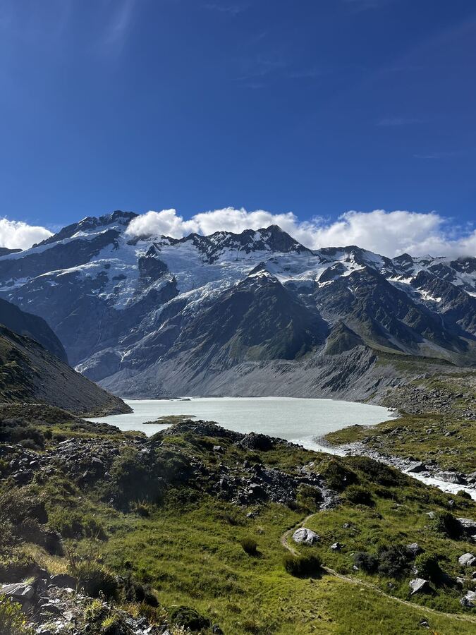 A milky glacial lake below a snowy mountain wall