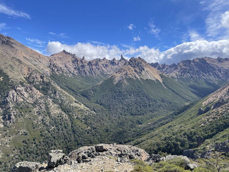 A forested valley running up to a crest of spiky rock towers
